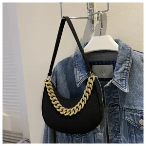 Primer plano de un bolso hobo de fieltro negro con cadena dorada decorativa moderna