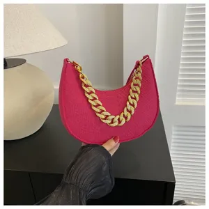 Bolso hobo de fieltro rosa fucsia con cadena dorada sostenido a mano en ambiente casual