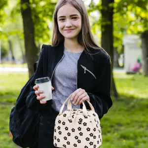 High-quality lifestyle shot of a floral corduroy lunch bag in a sunny park setting