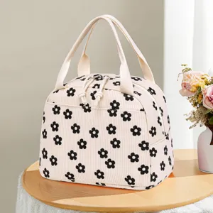 Close-up of beige corduroy lunch bag with black flower pattern on wooden table