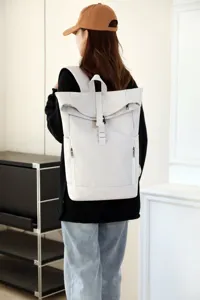 Lifestyle view of a beige roll-top backpack with magnetic buckle closure worn by a female model