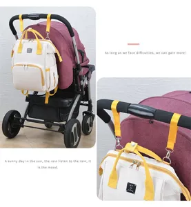 Detail of beige diaper bag with yellow straps attached to a stroller handle.