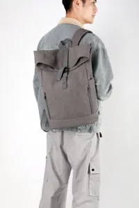 Rear view of an urban gray canvas roll-top laptop backpack with a magnetic buckle strap
