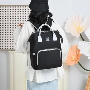 Large capacity black diaper bag backpack shown worn by model in lifestyle setting