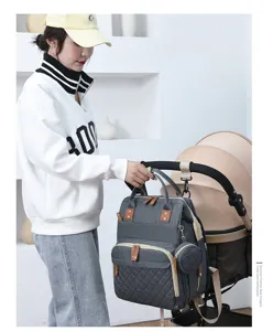 Graue multifunktionale Wickeltasche am Kinderwagen hängend, Model in Lifestyle-Umgebung