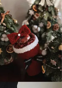 Detailed macro view of a festive red plush Christmas apple bouquet with bow and pearl
