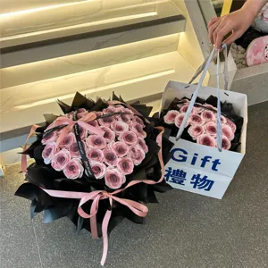 Vista detallada del hermoso ramo de rosas en forma de corazón con papel negro y cinta rosa.
