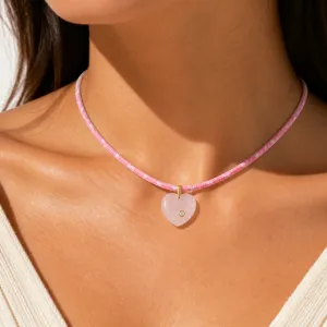 Close-up van een rozenkwarts hart hanger aan een roze gevlochten koord ketting