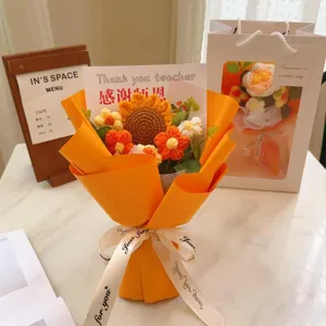 Detailed view of handmade knitted sunflower yarn bouquet with orange wrapping paper and card.
