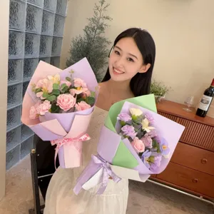 Une jeune femme tenant deux bouquets de fleurs de savon faits main dans une pièce confortable