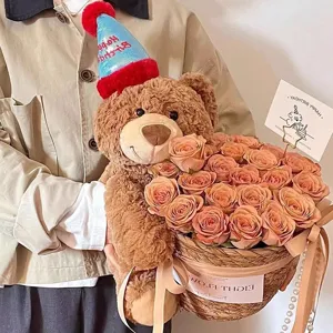 Gedetailleerd uitzicht op schattige teddybeer met perzik zeeproos boeket in emmer.