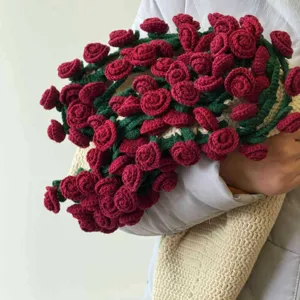 Handmade crochet rose blanket bouquet detail view, exquisite red flowers with green leaves.