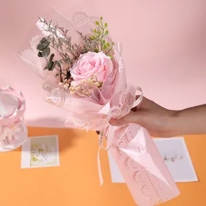 Handheld pink soap rose flower bouquet detail view featuring delicate lace wrapping and ribbon decor.