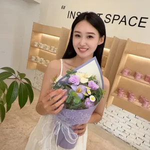 Elegant handheld bouquet with purple carnations and white lilies held by a model