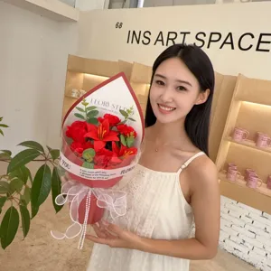 Smiling Asian woman holding a vibrant red soap flower bouquet with lilies and roses.