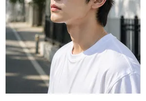 Detailed close-up shot of men's plain white t-shirt and minimalist necklace in outdoor light.