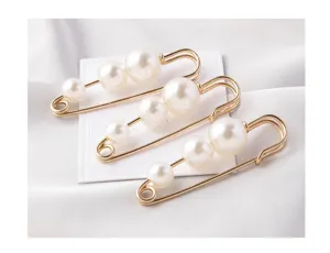 Set of three elegant gold-toned safety pin brooches with white pearls on white silk background.