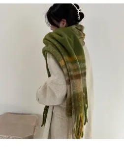 Detailed view of a thick green plaid mohair scarf with tassels worn with a beige coat
