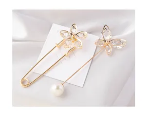Elegant detail of golden pearl brooch pins featuring crystal flower and butterfly designs.