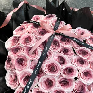Detailaufnahme des Rosen-Seifenblumen-Straußes mit schwarzer Verpackung und Schleife.