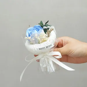 Detail shot of miniature artificial blue rose bouquet with white wrapping ribbon and sticker.