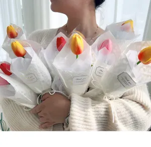 Vista dettagliata del singolo bouquet di tulipani finti confezionato in carta bianca.