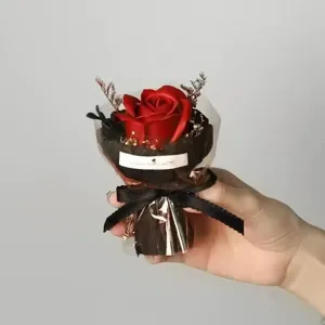 Close-up detail of a handmade red artificial rose bouquet wrapped in black paper with ribbon.