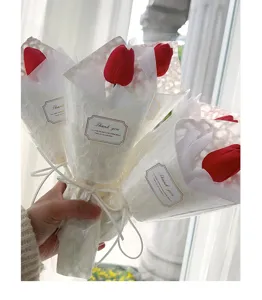 Bouquet di fiori di tulipano rosso artificiale confezionato in carta regalo bianca.