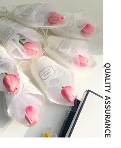 Bouquet di fiori artificiali di tulipano rosa a stelo singolo confezionato con carta bianca.