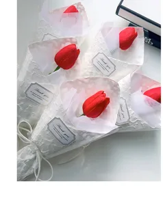 Vista dettagliata di un bouquet di tulipani artificiali rossi con elegante confezione bianca.