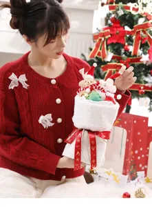 Detail of a festive white plush Christmas bear bouquet with red ribbons held by a woman