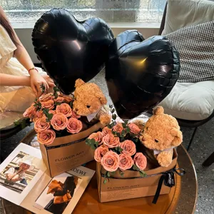 Vue détaillée du charmant coffret cadeau bouquet de fleurs ours en peluche et ballons noirs.