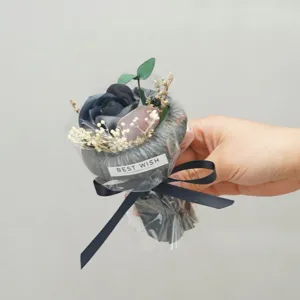 Close-up detail of a dark artificial flower bouquet wrapped in transparent paper with ribbon.