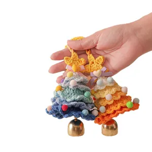 Handmade crochet Christmas tree hanging ornament with golden bell and colorful pom-poms.