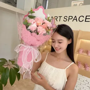 Young woman holding a romantic pink soap flower bouquet with carnations and roses.
