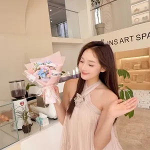 Elegant model holding a pink and blue soap flower bouquet in a modern art cafe setting