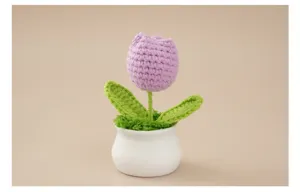 Makroaufnahme einer handgefertigten lila gehäkelten Tulpe in einem weißen Keramiktopf