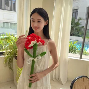 Handmade crochet red carnation flower held by a smiling woman in a bright interior room