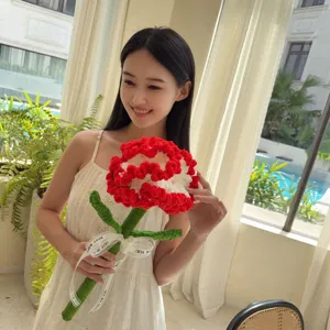 Young woman holding a large handmade crochet carnation flower with red and white petals