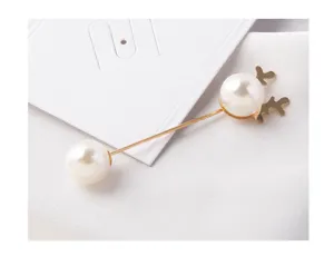 Close-up detail of an elegant pearl brooch featuring a golden reindeer antler design