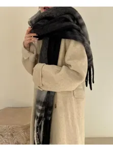 Detail of the thick grey plaid mohair scarf with long tassels worn over a coat