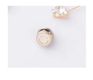 Macro detail of cream smiley face button and crystal triangle safety pin for clothing