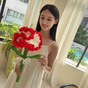 Close-up of a model holding a handmade red and white crochet carnation flower bouquet