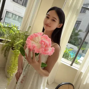 Young woman holding a handmade pink and white knitted carnation flower bouquet.