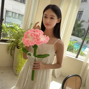 Beautiful handmade crocheted pink carnation flower held by a model as a warm gift idea.