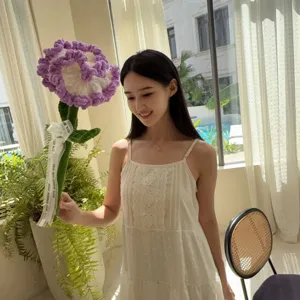 Handmade purple and white crochet carnation flower held by an Asian model in a room