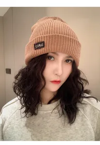 Primer plano de un gorro de punto acanalado marrón cálido usado por una modelo femenina