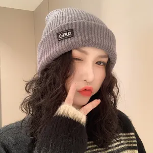 Stylish gray winter ribbed knit beanie hat for women with a decorative SURED patch detail