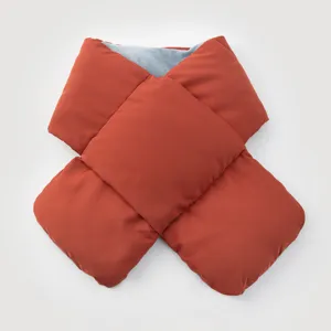 Detail view of a padded cross-over winter scarf in terracotta with grey fleece lining
