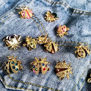 Macro detail of various colorful rhinestone beetle and ladybug brooches on denim pocket